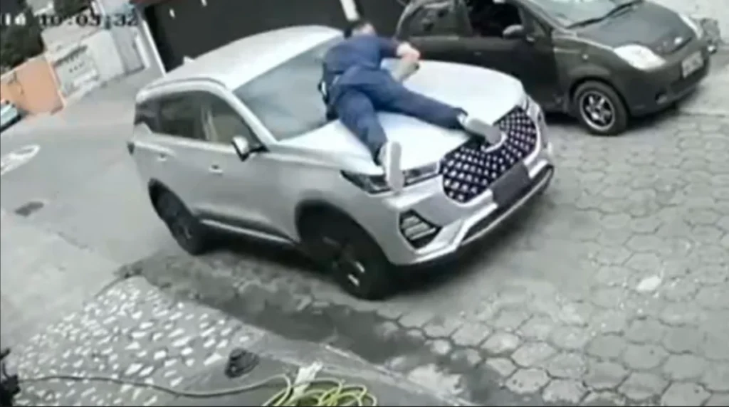 Se colgó del capó para evitar que le roben el carro