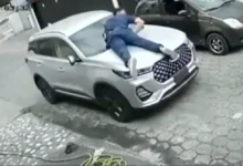 Se colgó del capó para evitar que le roben el carro